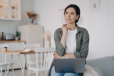 Freelancer geleceği planlıyor ve hayal kuruyor. Spahish kadın evde bilgisayarın önünde oturuyor. Çalışan proje üzerinde çalışıyor ve fikirler üzerinde düşünüyor. Rahat mutfağın karantinasında uzaktan çalışma.