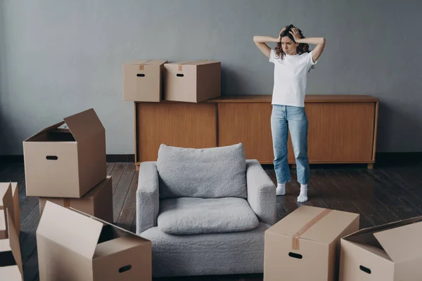 European woman has headache from moving alone. Young lady is exhausted with boxes unloading. Sad attractive girl is going to leave apartment. Annoyed young lady has problem with house.