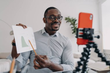 African american man showing chart to business partner by video call using smartphone. Black male business analyst shows a client or colleague economic graph, analyzes business data online.