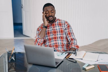 Tired online teacher. Exhausted afro man has online conference on pc. Sleepy businessman sitting with his eyes closed. Teacher is speaking to student. Remote study, distance learning. Online courses.