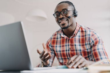 Friendly manager of client support service. African american man in headset receives calls. Online shop assistant is working from home. Teacher has remote lesson. Student gets distant education.