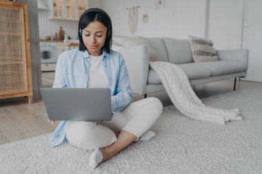 Kulaklıklı genç bir Arap kadın ve mikrofon yerde oturmuş laptopta görüntülü konuşma yapıyor. Avrupalı kız gülümsüyor ve bilgisayarda daktilo yazıyor. Freelancer 'ın internet oturumu var. Öğrencinin sanal dersi var..