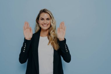 Teklifi kibarca reddeden genç bir kadının portresi. Dostça gülümseyen, olumlu bakışlarla el sallayan, el sallayan, mavi stüdyo arka planında, fotokopi alanı olan izole edilmiş bir şekilde ilgilenmeyen.