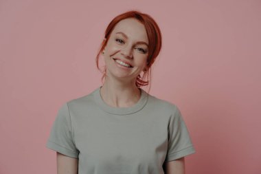 Mutlu insanlar konsepti. Keyifli görünüşlü, rahat, kızıl saçlı, neşeli, kaygısız, kırmızı saçlı kadın. İçerde rahatlayan, pembe arka planda izole edilmiş.