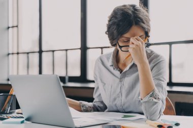 Aşırı çalışan İspanyol iş kadını evden uzakta çalışıyor, saatlerce bilgisayar başında oturuyor, gözlüğünü çıkarıyor, burnuna masaj köprüsünü kapalı gözlerle yapıyor. Yorgun çalışan baş ağrısı çekiyor.