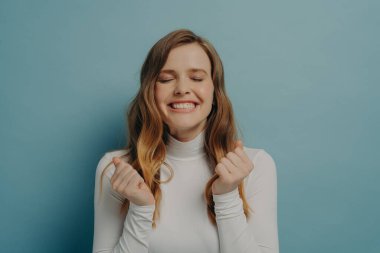 Rüyalar gerçek olacak. Heyecanlı genç bayanın portre görüntüsü. Yumrukları sıkılmış, gözleri kapalı. Mucizeyi bekliyor.