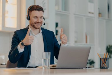 Mutlu erkek çalışanlar, jestlerin iş sunumundan memnuniyet duyması gibi video görüşmelerini mikrofonlu kulaklıklar kullanarak resmi giysiler giymesini sağlıyor. Yönetici işçi.