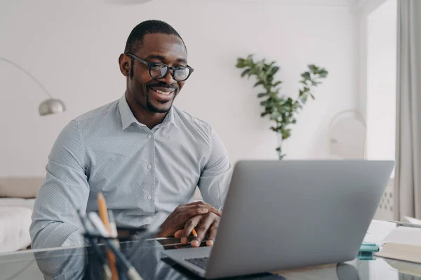 Online freelance job. African american man is speaking in front of camera of pc. Happy businessman in formal wear has video meeting in zoom. Remote conference or consultation at home.