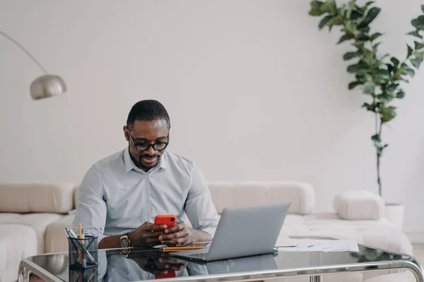 African American Businessman Looking Smartphone Screen Sitting Laptop Working Online — Zdjęcie stockowe