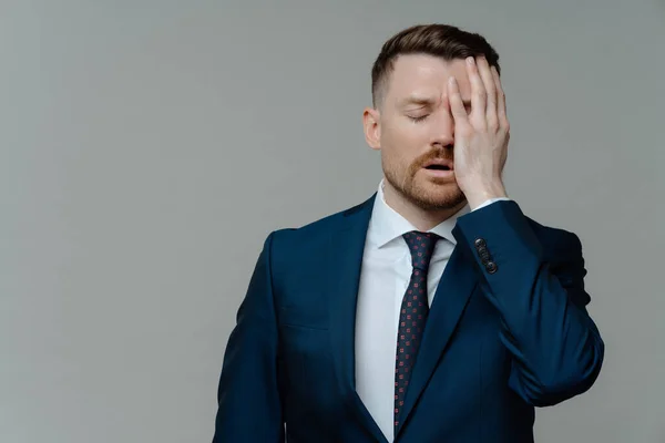 Stock image Horizontal shot of displeased bearded man manager makes face palm feels very tired dressed in formal outfit being depressed isolated over grey background with copy space for your advertisement