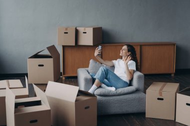 Excited girl having video call on phone in new apartment. Successful independent young woman. Mover shows her dream house. Mortgage loan and happy home owner concept.