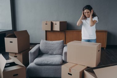 Happy young spanish woman relocates alone. Single lady moves and packing things. Girl packing cardboard boxes. European woman unpacking boxes in new house. Real estate purchase and mortgage concept.