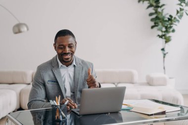 Man has online conversation or consultation on laptop. Teacher has distant lesson. Freelancer is working at home office. Remote african american worker is sitting in front of camera.