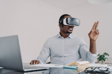 African american man in vr glasses. Businessman has virtual meeting. Freelancer is working on design project on laptop. Modern digital technology and electronic devices for business and creativity.