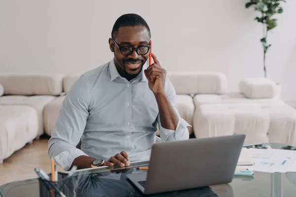 Uśmiechnięty Afrykański Biznesmen Rozmawiający Przez Telefon Patrzący Laptopa Biurze Czarny — Zdjęcie stockowe
