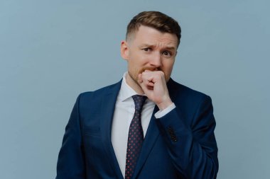 Stresli, tıraş olmamış takım elbiseli işadamı gergin, depresif erkek ofis çalışanı açık mavi arka planda dururken duygu sömürüsü yapıyor. İş sorunları ve başarısızlık kavramı