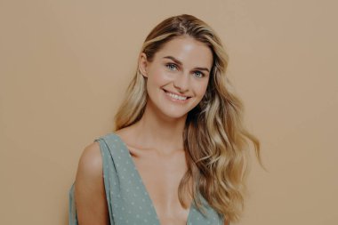 Uzun sarı saçlı, açık mavi gece elbisesi giyen, mutlu ve olumlu bir ifadeyle kameraya bakan ya da sevgilisiyle romantik anlar yaşayan kadın modelin yakın bir portresi.