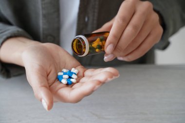 Elinde ilaç şişesi olan kadın beslenme takviyeleri, vitaminler veya ilaçlar almak için avuç içine hap döker. Ağrı kesici ya da uyku hapı alan kadınlara yaklaşır. Sağlık ve sağlık hizmetleri