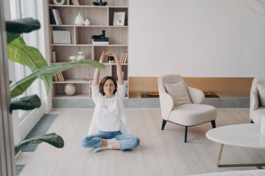 Mutlu çekici kadın yerde yoga ve meditasyon yapıyor. Avrupalı kız nilüfer çiçeği pozunda oturuyor. Evde sabah sporu. Karantinada zihinsel sağlık, rahatlama ve stres giderme.