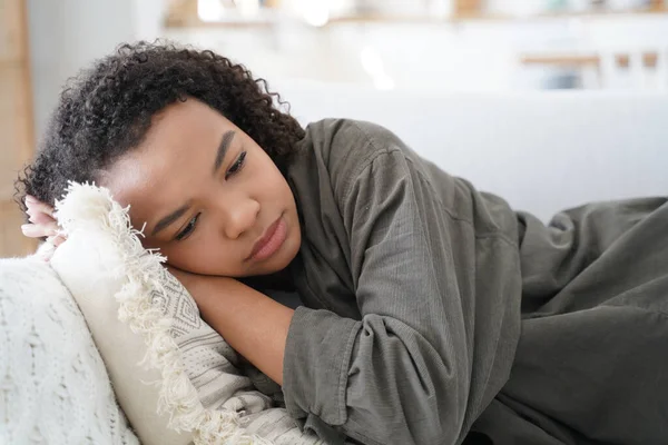 stock image Tired african american teen girl had a bad day lying on sofa at home alone. Frustrated biracial female feels mental exhaustion, suffer from teenage problems, looks melancholic. Lack of energy, fatigue