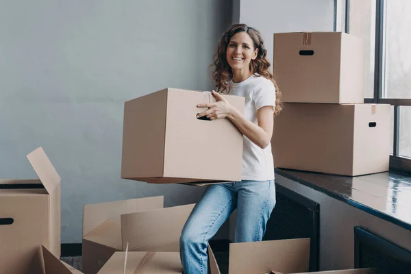 Happy home owner. European girl carrying box. Hispanic woman unpacking boxes. New apartment, mortgage and independence concept. Real estate advertising mockup.