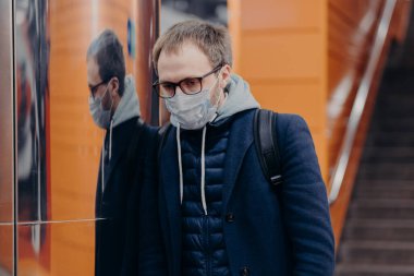 Hastalıklı adam koronavirüse karşı koruyucu maske takıyor metro ya da metroda poz veriyor kendini bulaşıcı hastalıklardan koruyor, sırt çantası taşıyor. Avrupa 'da Covid-19 sırasında toplu taşıma