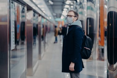 İnsan yolcunun metro istasyonunda pozu, koronavirüs zamanında tıbbi maske takması, treni beklemesi, toplu taşıma araçlarıyla işe gitmesi. Virüs, hastalık ve grip konsepti