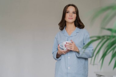 Büyük boy çizgili boka giymiş güzel kadın yatay atış çekici tuvalet var, fincan kahve veya kahve, standları boş kopya alanı reklam içeriği veya metin için sol ile kapalı tutan