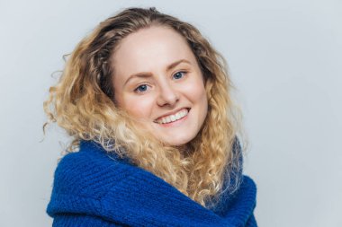 Oldukça sıcak mavi gözlü genç güzel kadın gülümsüyor, sağlıklı cilt ve beyaz mükemmel dişler, sıcak süveterin içinde giyinmiş sevinir açık mavi renkli, modelleri kapalı izole hafta sonları geliyor.