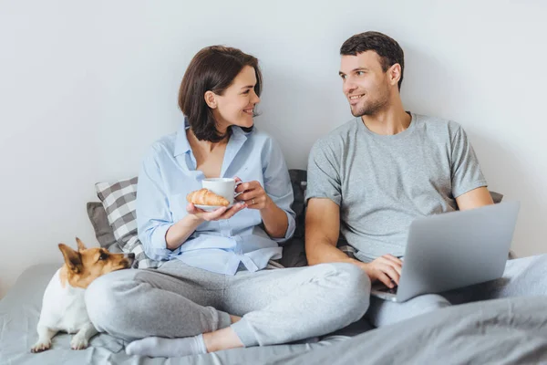 스러운 커플의 침대에 노트북 컴퓨터를 즐거운 온라인 테리어 침실에서 호스트 — 스톡 사진