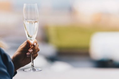 Nazik manikür ile tanınmaz erkek karşı arka plan bulanık cam pırıltılı beyaz şarap veya şampanya tutar. İnsanlar, eğlence ve içki kavramı