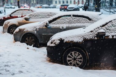 Şehirde karla kaplı arabalar var. Şiddetli kar fırtınası kasabayı felç etti. Otoparkta karlı araçlar. Kış sahnesi ve kötü hava koşulları