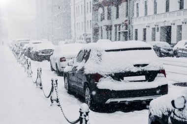 Kar fırtınası, yoğun kar yağışı veya kar fırtınası konsepti. Kar yağışlı kış havasında karla kaplı sıra sıra arabalar. Otoparktaki araçlar. Felç Taşımacılık