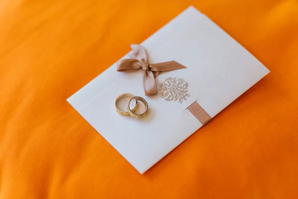 Весільна Концепція Золоті Обручки Лежать Білій Картці Запрошення Помаранчевий Фон — стокове фото