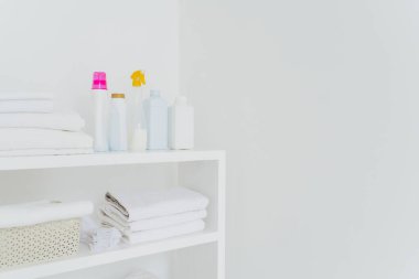 Yumuşak krem sıvısı olan bir yığın beyaz havlu. Bilgileriniz için kopyalama alanı olan beyaz arkaplan. Temizlik konsepti. Doğal ışık