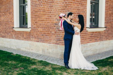 Romantik gelin ve açık yeşil çimen, antik builduing yakın dururken damat kucaklama yatay dikey birbirlerinin gözlerine bak, onların aşk ve romantizm ifade. Evlilik kavramı