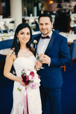 Gelin ve damat ile bardak şampanya, düğünlerini kutlamak, Festival salonunda Konuklar için bekleyin, hoş gülümsüyor yüzlerinde var. İyi günler ve unutulmaz anlar evli çift keyfini çıkarın