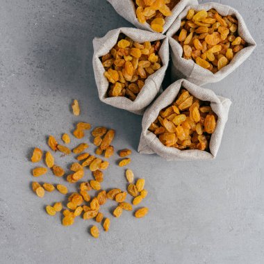 Yukarıdan fotoğraflanan çuvallar içinde kurutulmuş üzüm altın kuru üzüm, gri arka plan üzerinde izole. Kurutulmuş meyve ve yeme konsepti