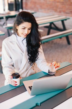 İnsanlar ve yaşam tarzı kavramı. Mutlu bir şekilde seyir lezzetli kahve içme perde Beyaz önlük ile dizüstü bilgisayar, çalışma masasında oturan kırmızı manikür sahip şirin esmer kadın Üstten Görünüm