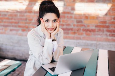 Sevimli yüz ve kırmızı olan çok güzel esmer kadın manikür dizüstü bilgisayar ücretsiz internet bağlantısı ile yüksek hızlı kullanarak ailesiyle birlikte sohbet kullanarak masada oturan giymiş Beyaz önlük