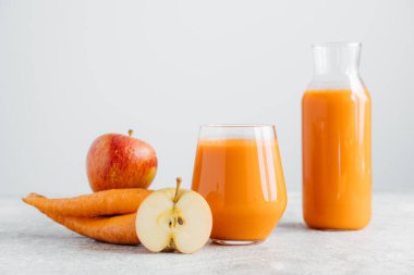 Cam kavanozda detoks içeceği, beyaz arka planda elma ve havuç dilim. Tazelenmiş ev yapımı doğal havuç içecek, olgun meyve ve sebze.