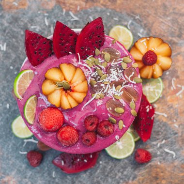 Gıda ve sanat konsepti. Güzel tasarlanmış meyve. Pembe pitaya ile dondurma, kırmızı ejderha meyve dilimleri, çilek, ahududu, kireç, hindistan cevizi gevreği, kabak çekirdeği
