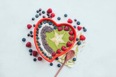 Ahududu, yaban mersini, cocao uçları, yakın ahşap kaşık Kalp şeklinde kase, beyaz backgound üzerinde izole. Ispanak kasesi. Taze meyve