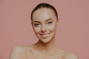Makyajlı, taze tenli, cildine önem veren, nazikçe gülümseyen ve doğrudan kameraya bakan genç ve güzel bir manken. Kozmetik, kaplıca, yüz tedavisi kavramı