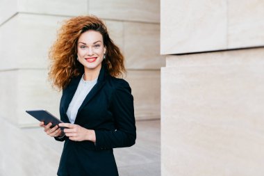 Muhteşem erkek siyah elbiseli, kıvırcık Gür saçları, mavi gözleri ve kırmızı olması hoş tablete kısa mesaj yazarken gülen dudakları boyalı. Başarılı işkadını şık giysileriyle tablet kullanma