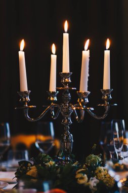 Koyu arka plan veya oda karşı beş beyaz yanan mumlar güzel şamdanla dikey bir kadeh. Antika mumlar dekore edilmiş hizmet tablo