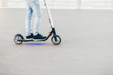 Yatay atış bilinmeyen erkek, spor ayakkabı, dar kot pantolon giyer, yaz saati sırasında sürücüler elektrikli scooter üzerinde duruyor. İnsanlar ve taşıma kavramı