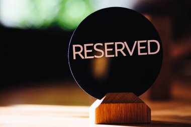 Reserved sign on restaurant table. Booked desk in cozy cafe against blurred background. Booking and reservation concept. Book seat for costumer. clipart