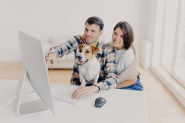 Aile fotoğrafı favori web sitesinden alışveriş yapıyor, birlikte vakit geçiriyorlar, bilgisayar monitörüne odaklanmış komik bir köpek, ortak çalışma alanında oturuyor. Evcil hayvanlara odaklan. Dijital pazarlama