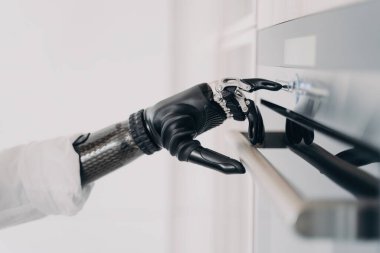 Siber kol protezi kavrar ve fırını açar. Engelli, ampüte, yemek pişirmeye hazırlanıyor..